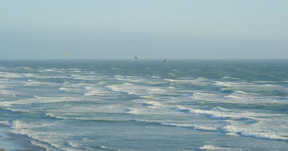 Sailboats in the ocean as waves roll to the shore