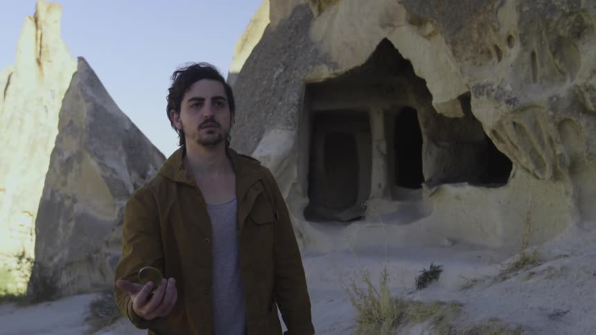 A man in a brown jacket looks at his compass