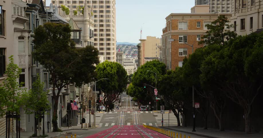 A city street with buildings and cars driving and pedestrians crossing