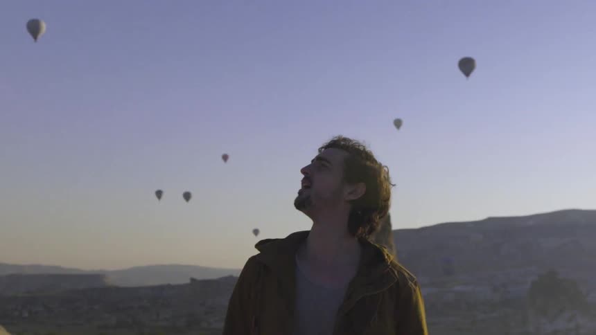 A man observes floating hot air balloons at sunset
