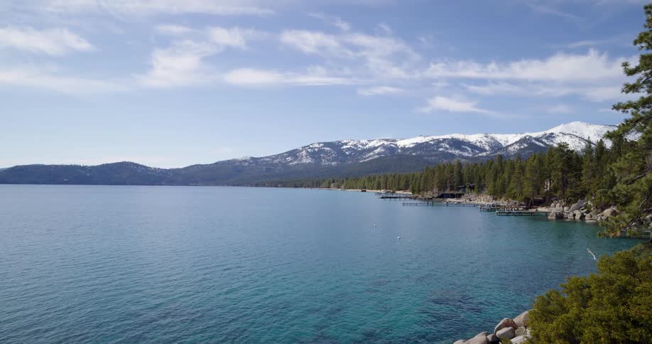 A large lake with a rocky shore and a large snow capped mountain in the background