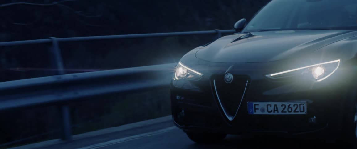 A car drives on a rural road in the dark