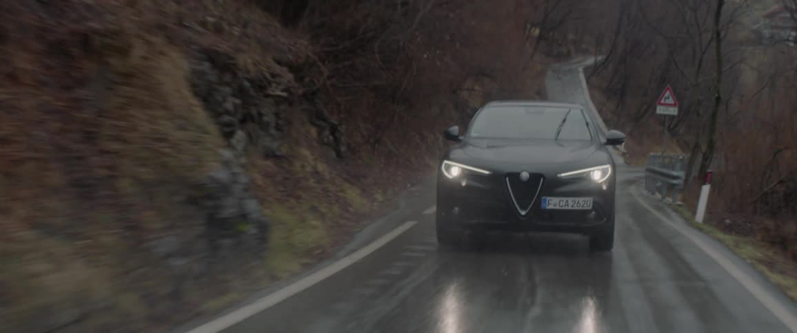 A car drives on a rural road in the rain