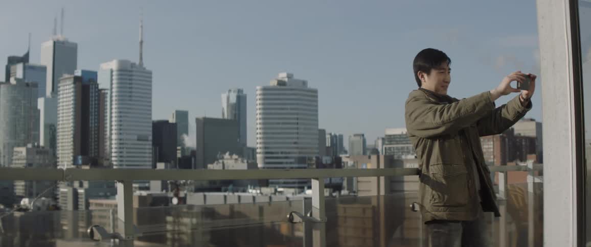 A man is looking at the view from the roof and takes a selfie