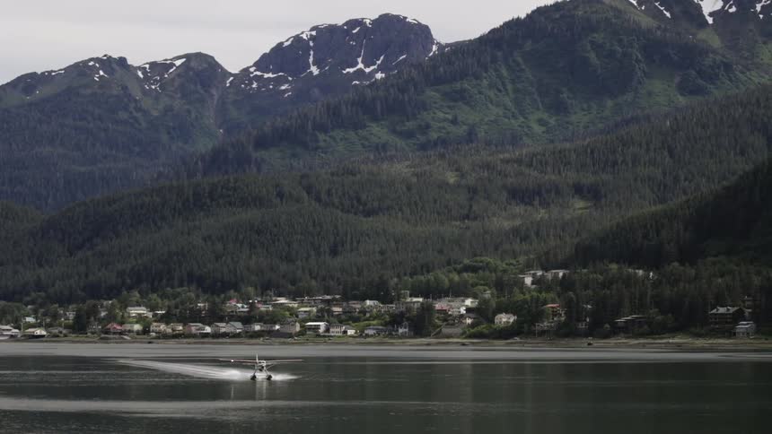 A seaplane moves across the water in a mountainous landscape