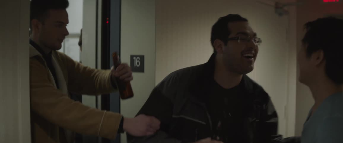 A man walks down the hall with a friend and a drink before being pulled into an elevator