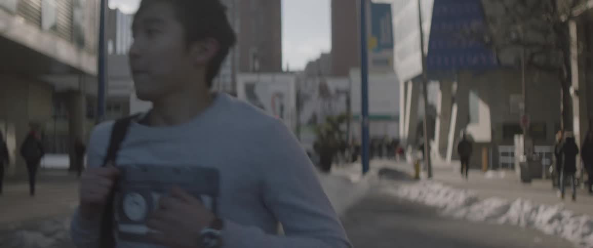 A man is jogging down the street checking his watch