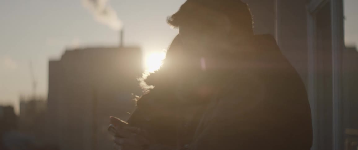 Man and woman stand on a balcony looking at a phone