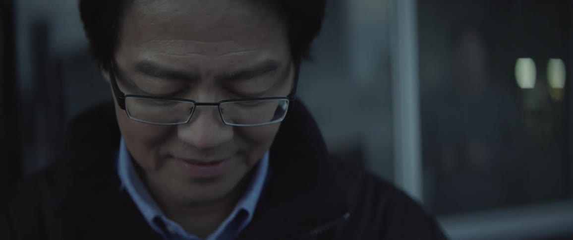 Man outside looking downward and smiling
