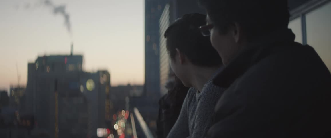 People stand outside a building balcony at dawn talking