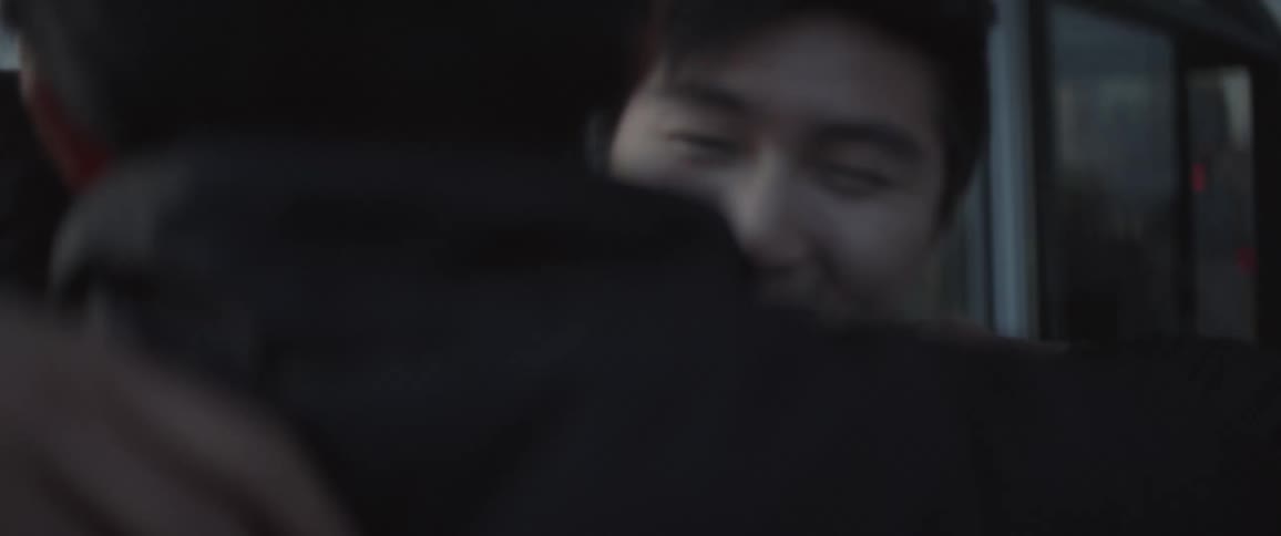 Two men hug while smiling