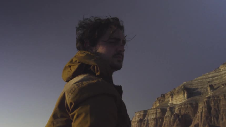 A man stands before a mountain gazing around