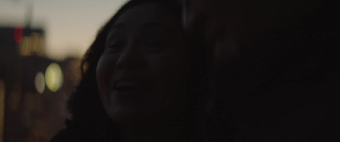 A man and woman standing outside laugh and talk