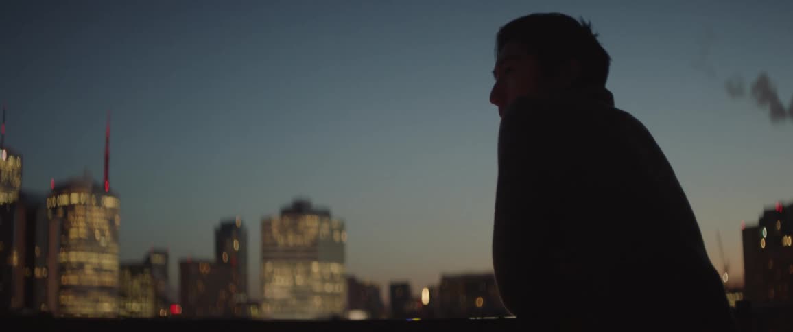 Man standing on balcony looking at city view at night