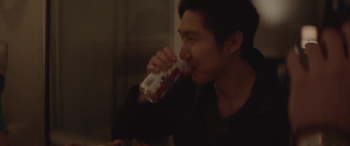 People around a table make a toast with beer bottles and can and drink