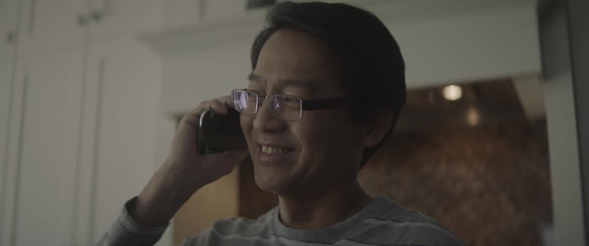 A man is talking on the phone and he smiles