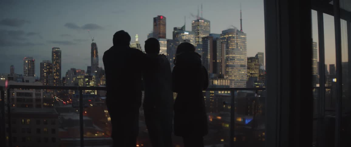 Three people stand on a balcony