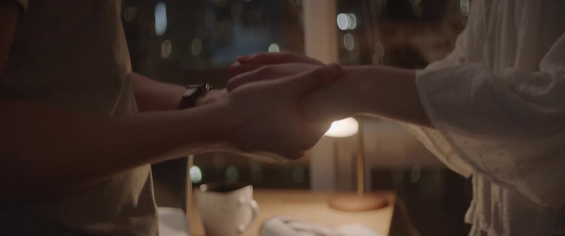 A man and woman hold hands in an apartment