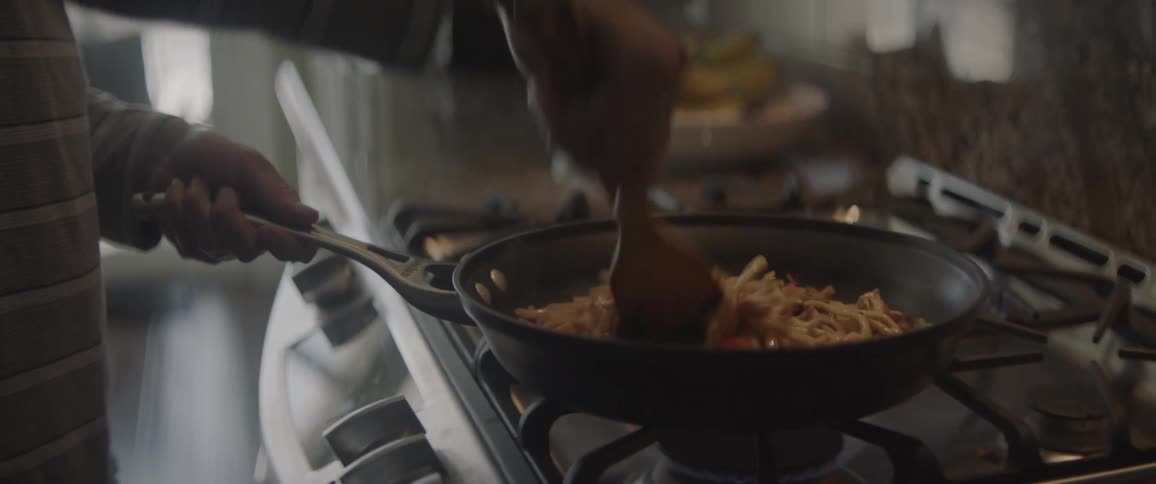 A person is preparing noodles in a pan