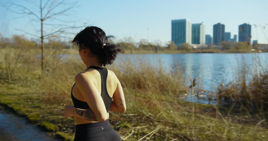 Woman runs on a trail near the water while a bird takes flight