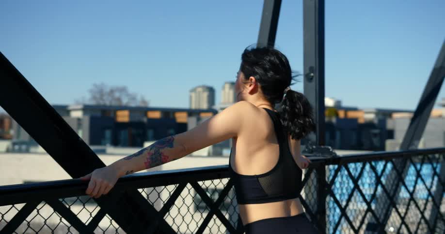 A woman standing on a bridge looking over the neighbourhood and train tracks