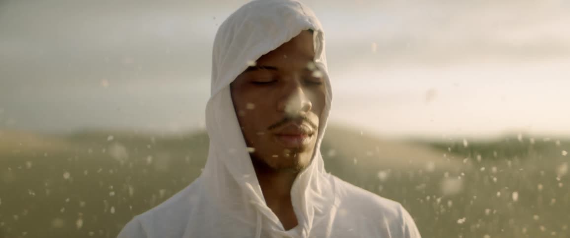 Dust and sand particles blow past a man as he meditates in the desert