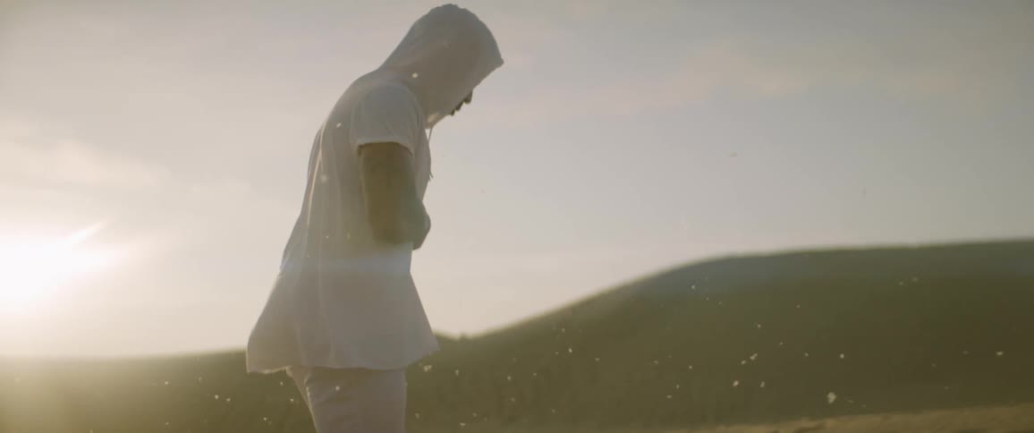 A man walks barefoot in a desert at sunset