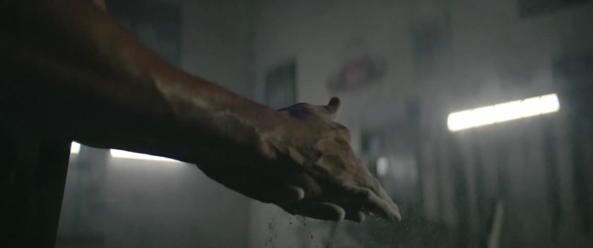A man rubs chalk on his hands before working out
