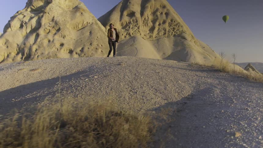 A man climbs a small hill in a desert area