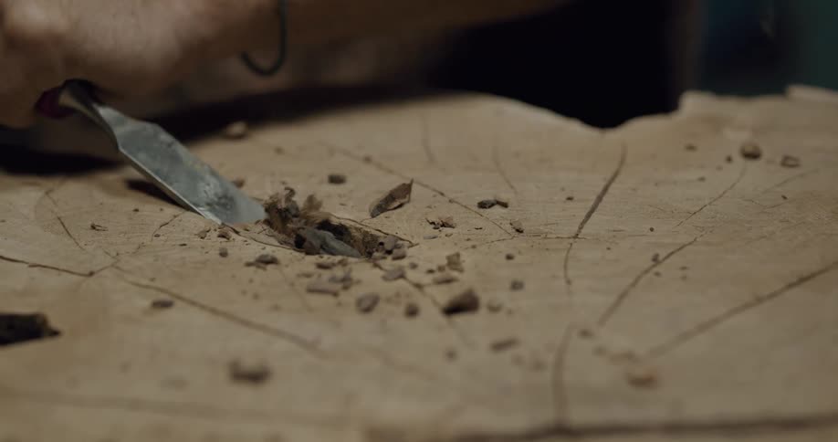 A person with a chisel carving wood