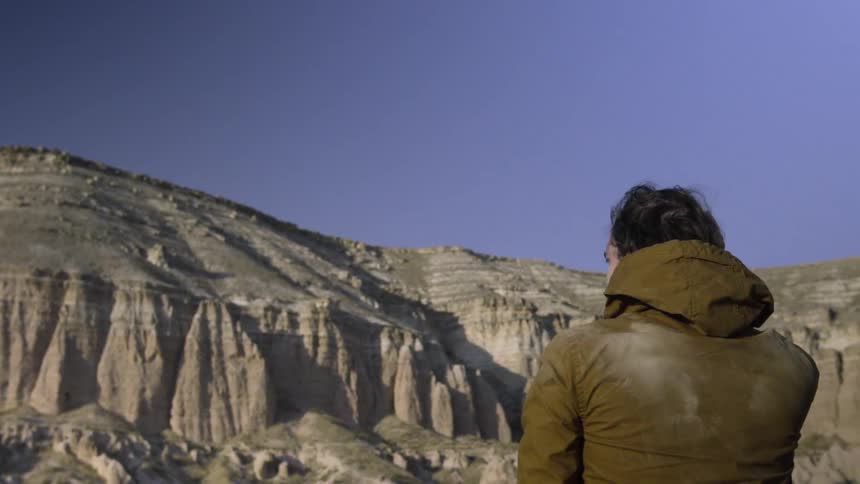 A man overlooks a rocky valley on a sunny day