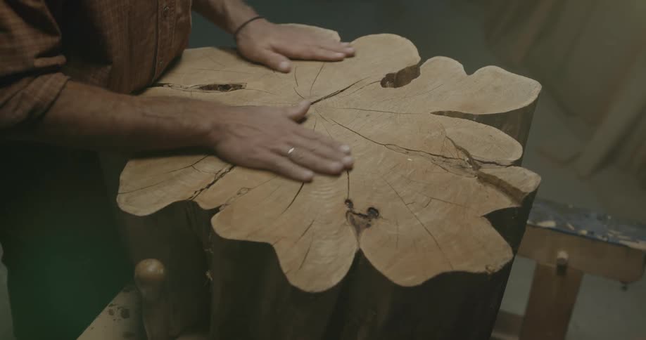 A man runs his hands over a large piece of wood