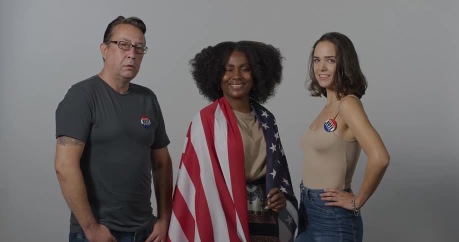 Three people one with an american flag over her shoulders pose for a photo