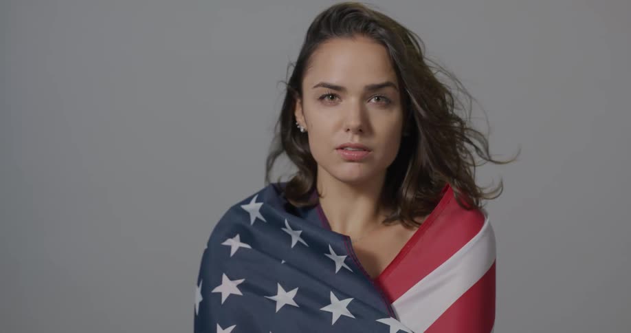 A teenage girl wraps a flag around her shoulders as she poses for a photo