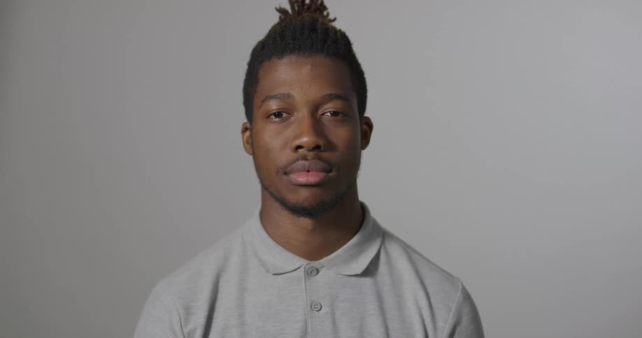 A young black male wearing a grey shirt looks up and stares directly ahead