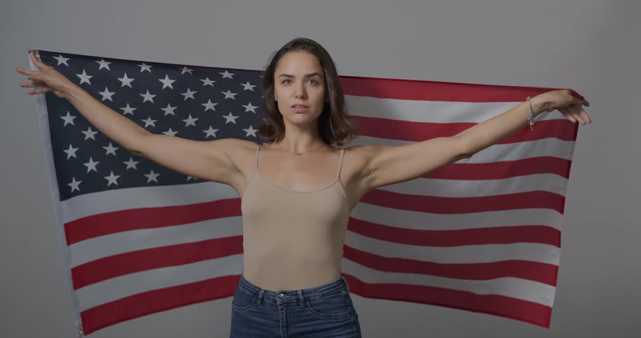 A teenage girl poses with the american flag around her shoulders