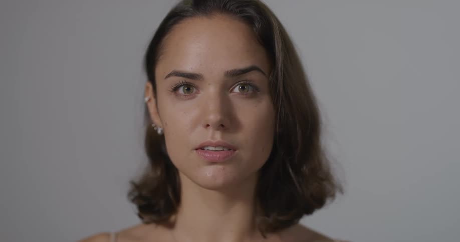 Woman wearing earrings in her right ear lifts her head and blinks her eyes