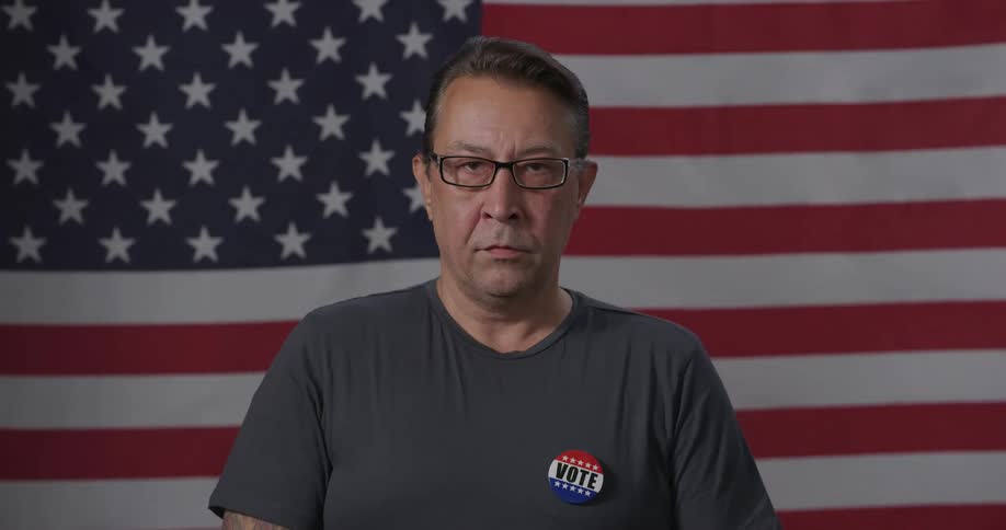 A man is wearing a pin that says vote