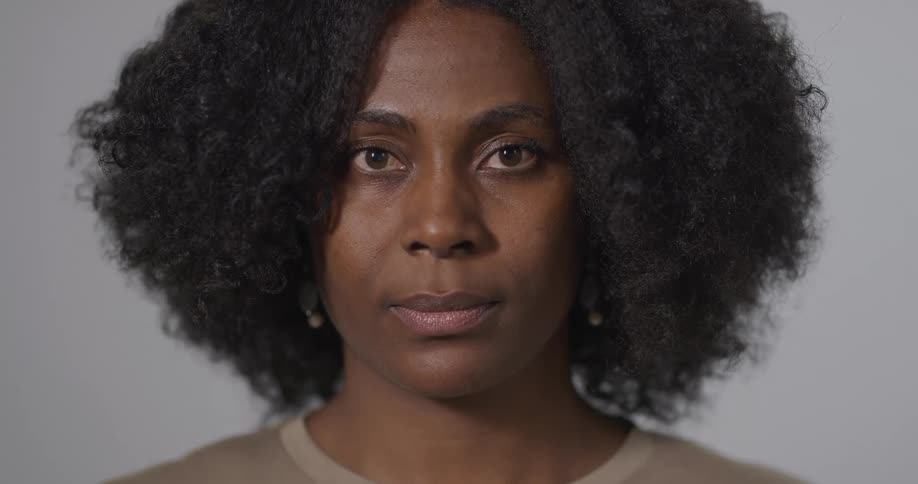 Black woman with frizzy curly hair faces the camera with eye contact
