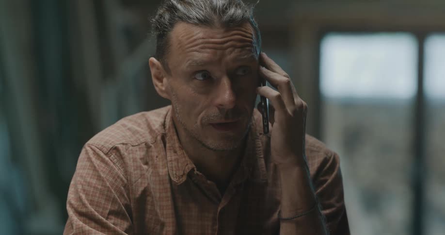 A guy in indoors and talking on a cellphone