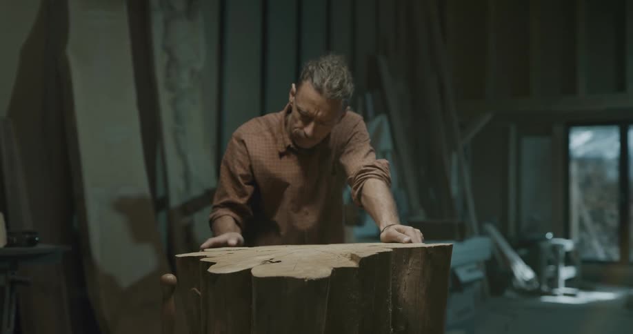 Man checks smoothness of carved wooden block in workshop