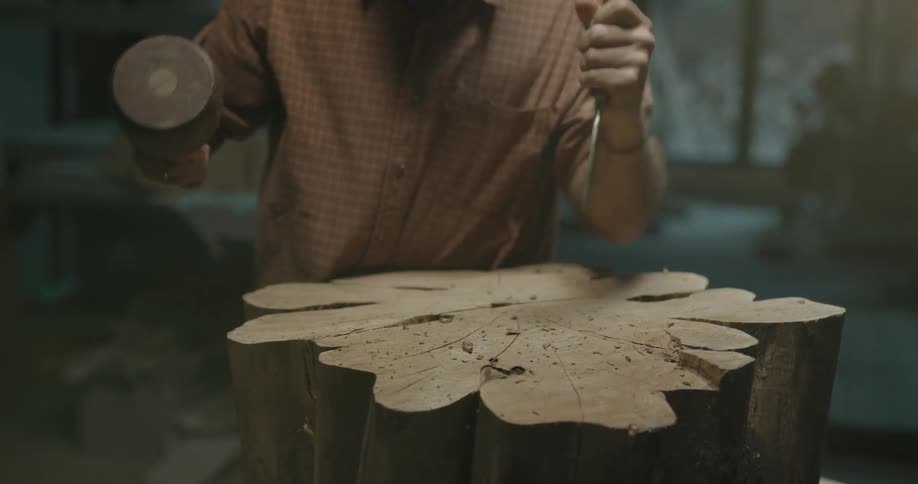 Man carves wood with a chisel in workshop