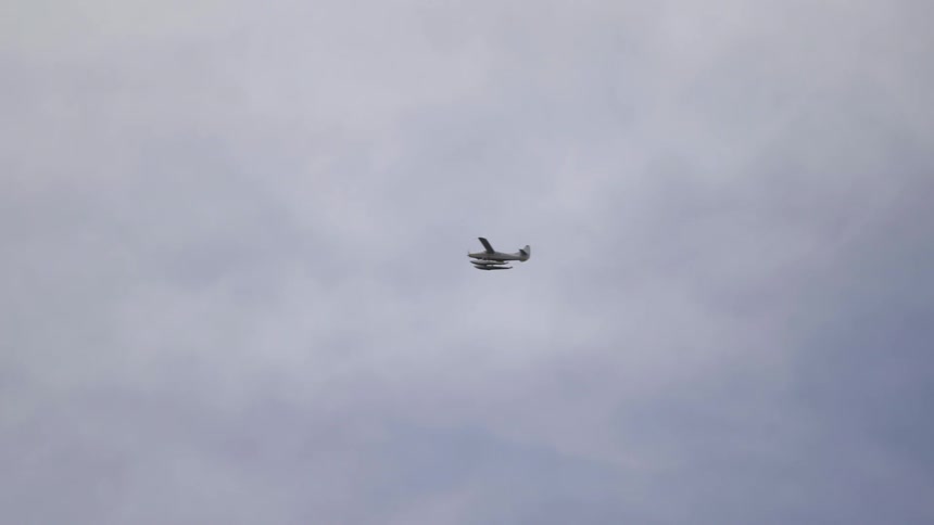 A small plane flying across a cloudy sky