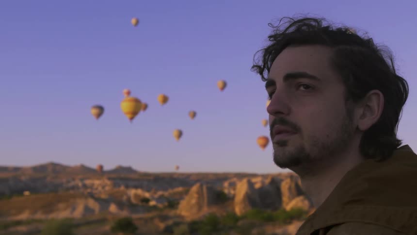 A man looks up at floating hot air balloons