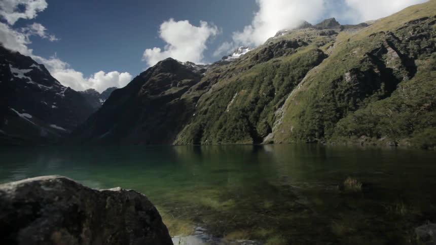 White clouds and blue sky over a clear mountain lake