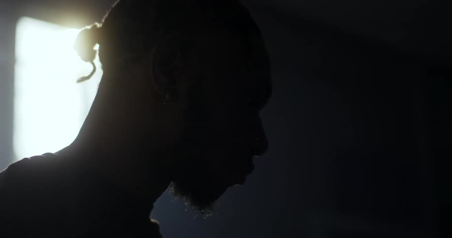 A mans silhouette is illuminated by sunlight coming through a small window