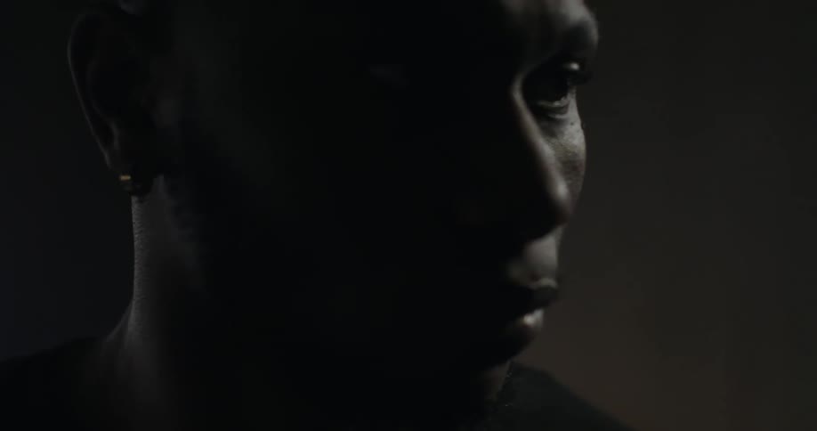 Man stands in shadowy room looking intently
