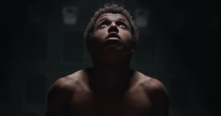 A man shakes and rubs his head in the locker room
