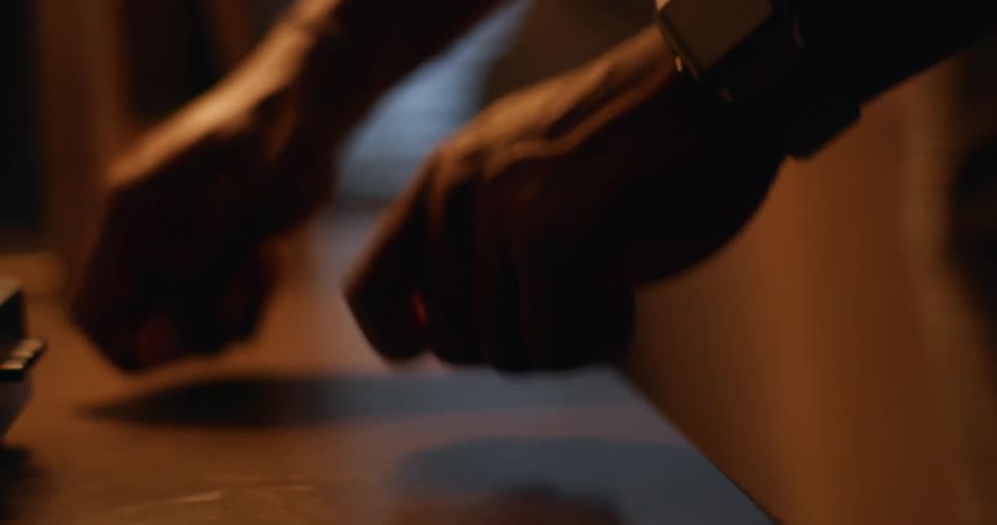 A man drums his fist on a table as he listens to music on a record table