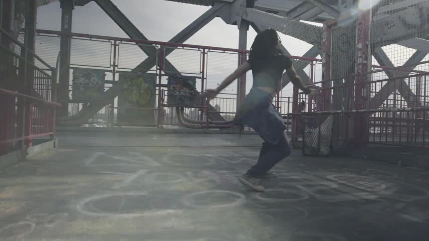 A woman is dancing on a platform as a person walks past